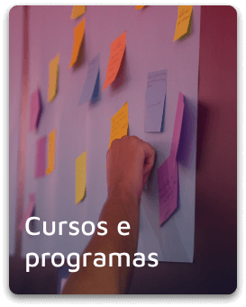 Imagem de uma pessoa colando post-it em um quadro com o título "cursos e programas"
